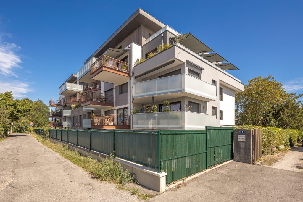 Résidence moderne avec balcons et terrasses boisés.