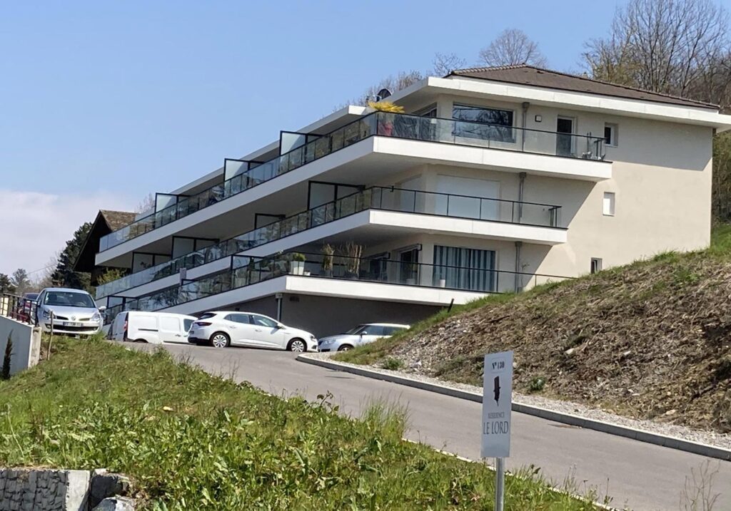 Résidence moderne avec balcons et voitures garées.