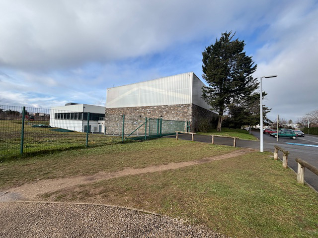 Bâtiment industriel avec clôture et arbres
